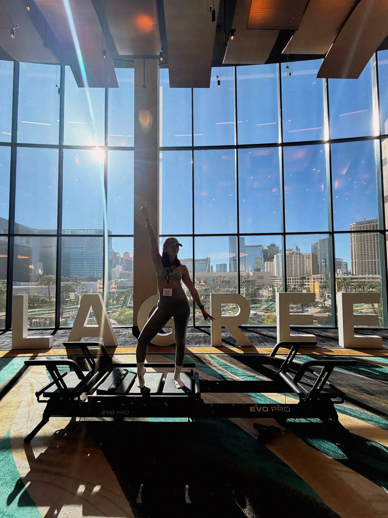 Ciarra on a Lagree machine at the Lagree Summit with a city skyline behind
