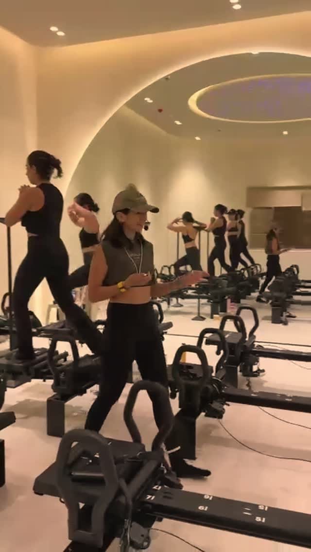 Ciarra in a cap leading a full Lagree class across rows of machines